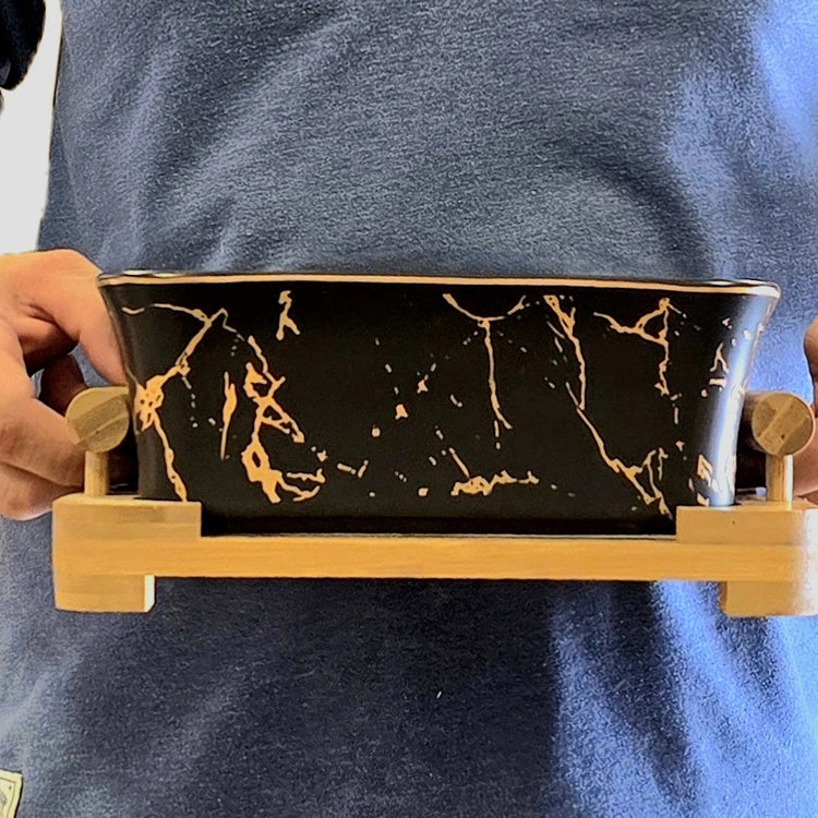 Black ceramic serving bowl with wooden stand